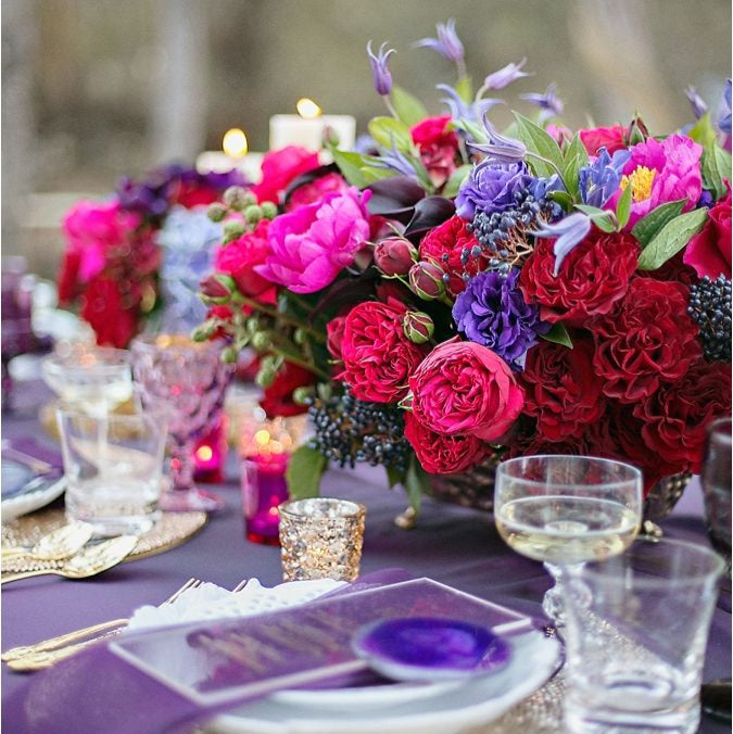 Colorful floral arrangement on a table with candles and glasses