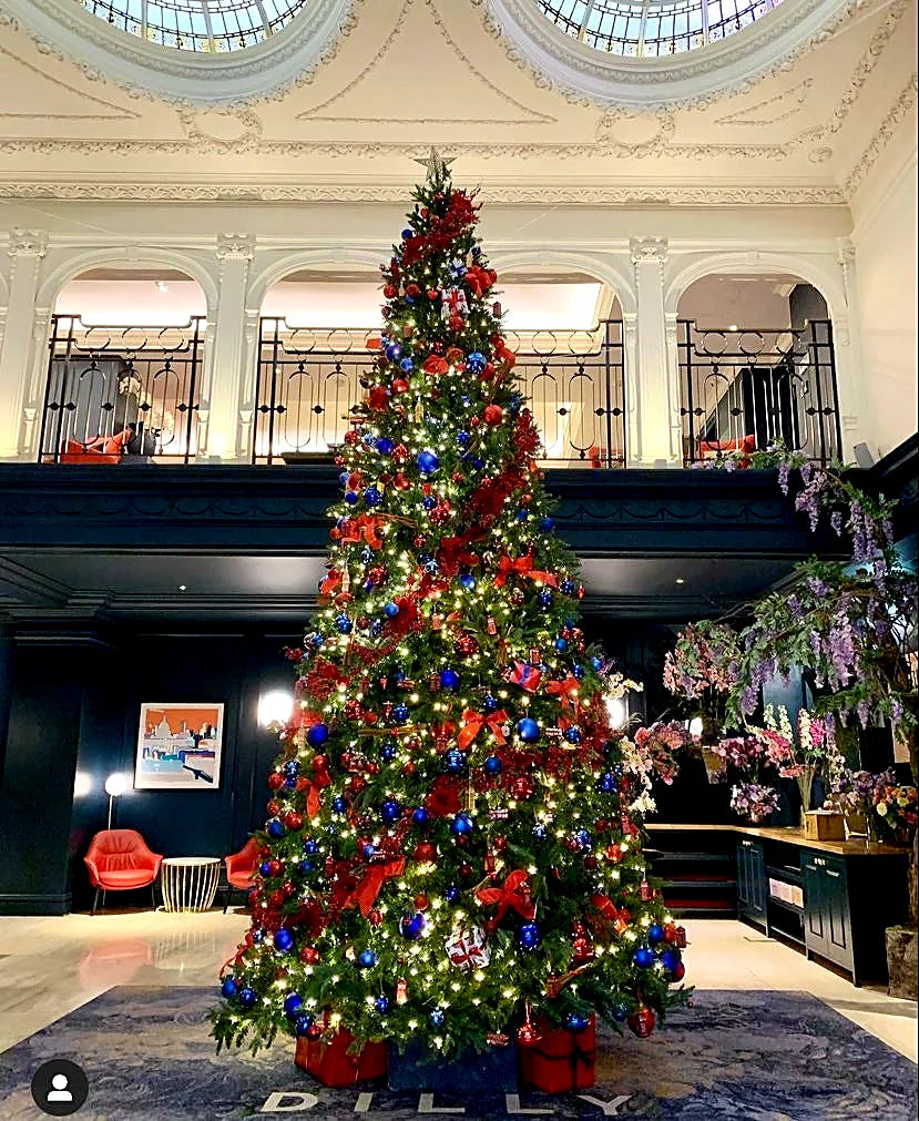 Red, blue and gold decorated Christmas tree in a London hotel lobby by Pulbrook & Gould