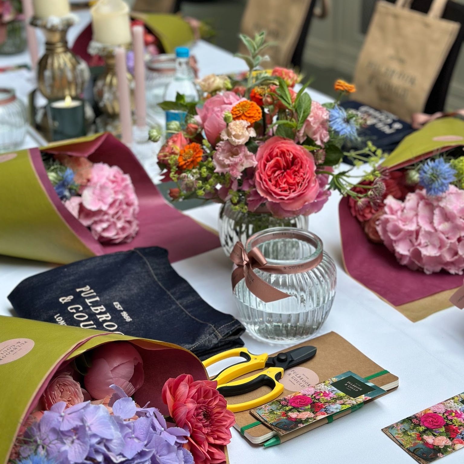Table laid for a private flower workshop with bouquets, aprons and secateurs