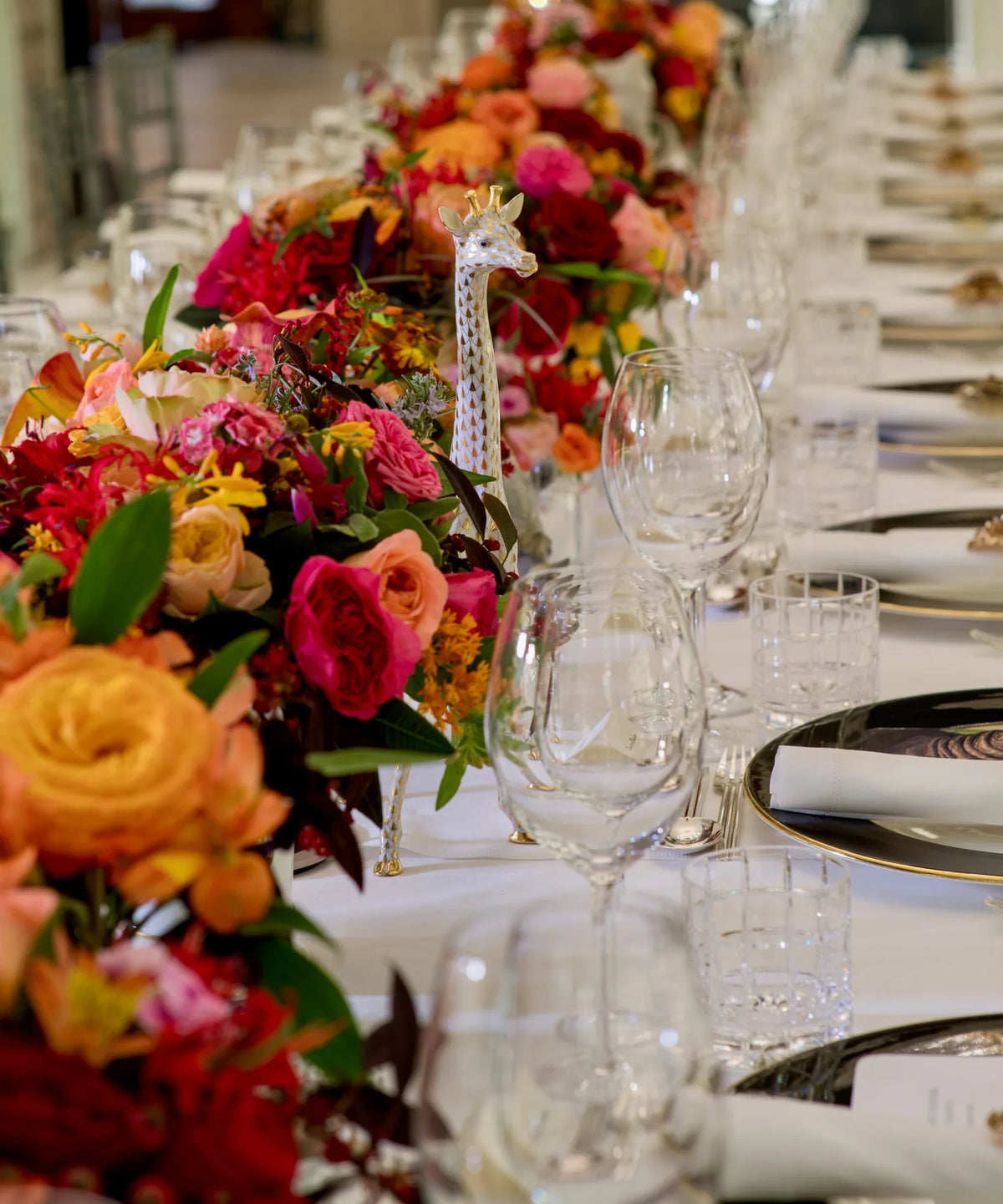 Long table centrepiece of orange, red and pink roses at a formal corporate dinner, event floristry, by Pulbrook & Gould
