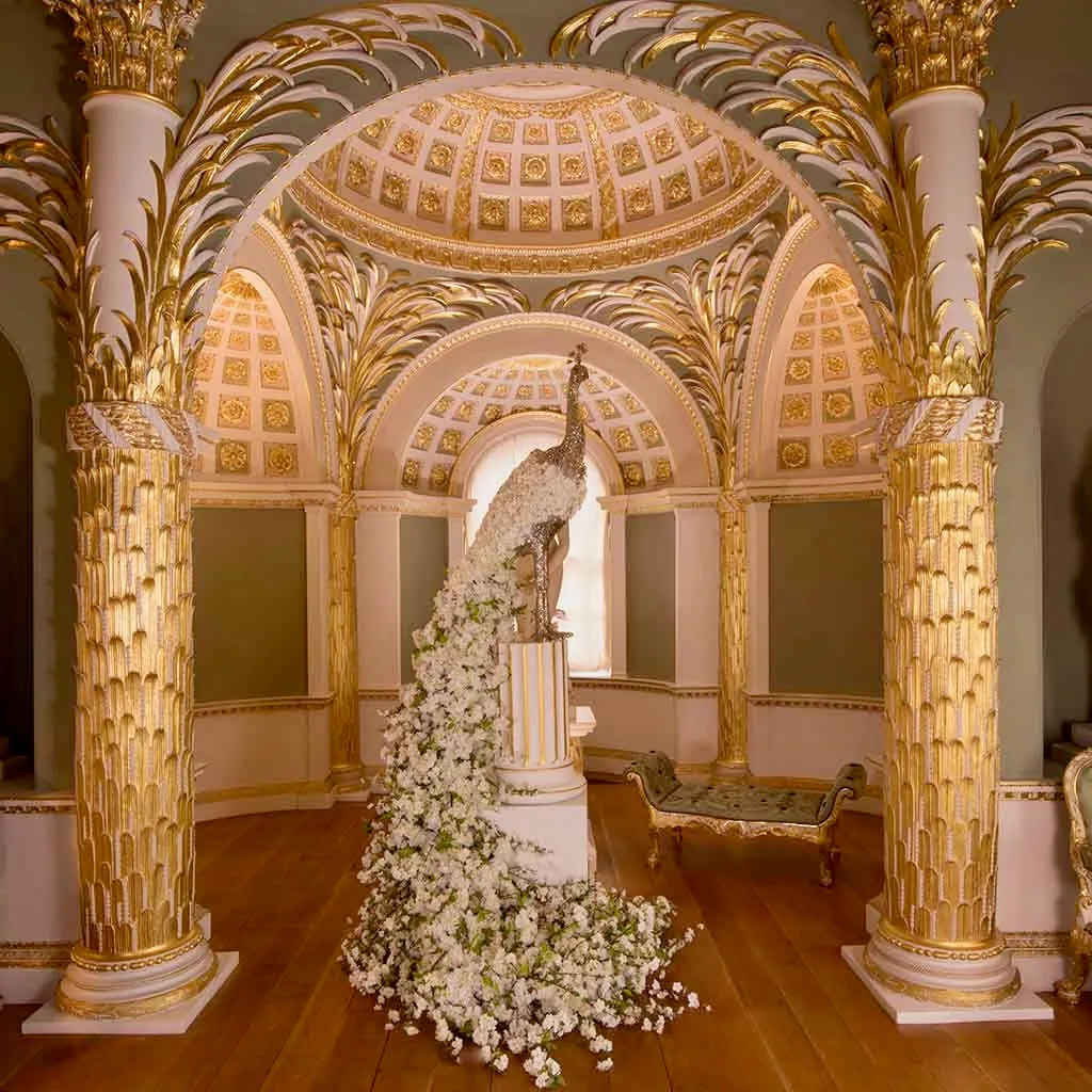 Grand gilded domed hall with a golden peacock statue cascading with white flowers, large-scale event, by Pulbrook & Gould