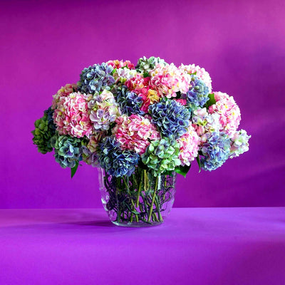 
                    
                      Mixed faux hydrangea vase arrangement by Pulbrook and Gould in clear glass vase with silk faux flowers
                    
                  