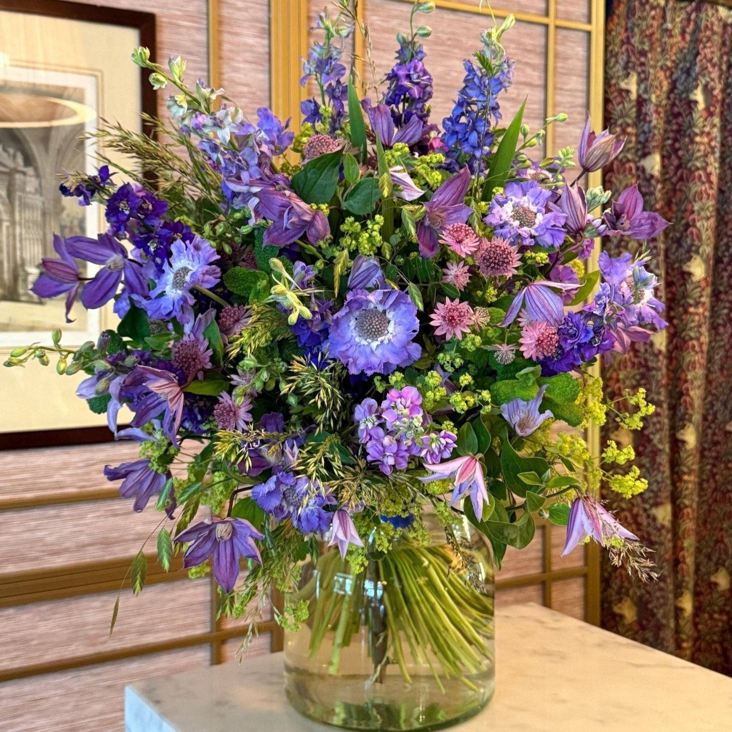 Summer Blues arrangement with delphiniums, clematis and scabiosa in a glass vase by Pulbrook & Gould