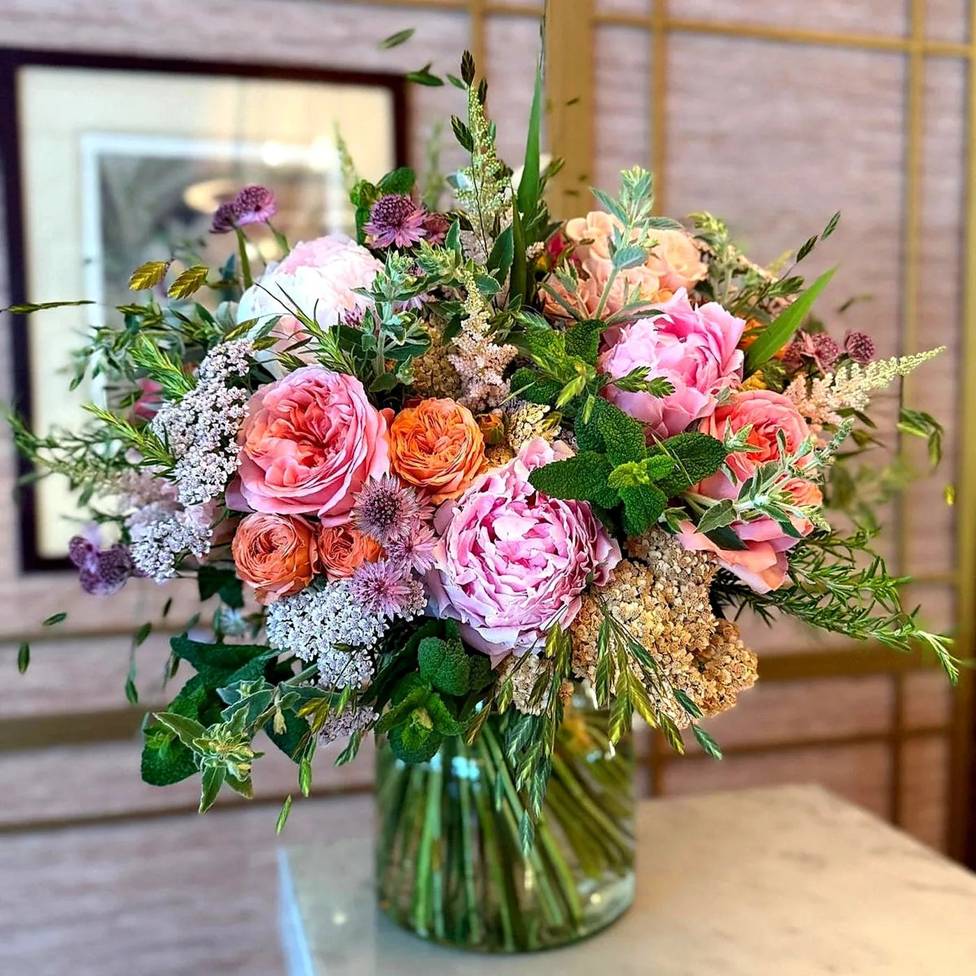 Summer Joy Pulbrook Gould hand tied bouquet in pastel pink, orange and purple with leafy foliage accents