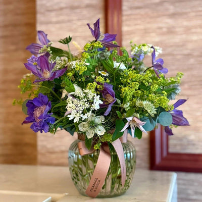 
                    
                      Summer Posy by Pulbrook and Gould hand tied posy bouquet with purple clematis and lime green flowers
                    
                  
