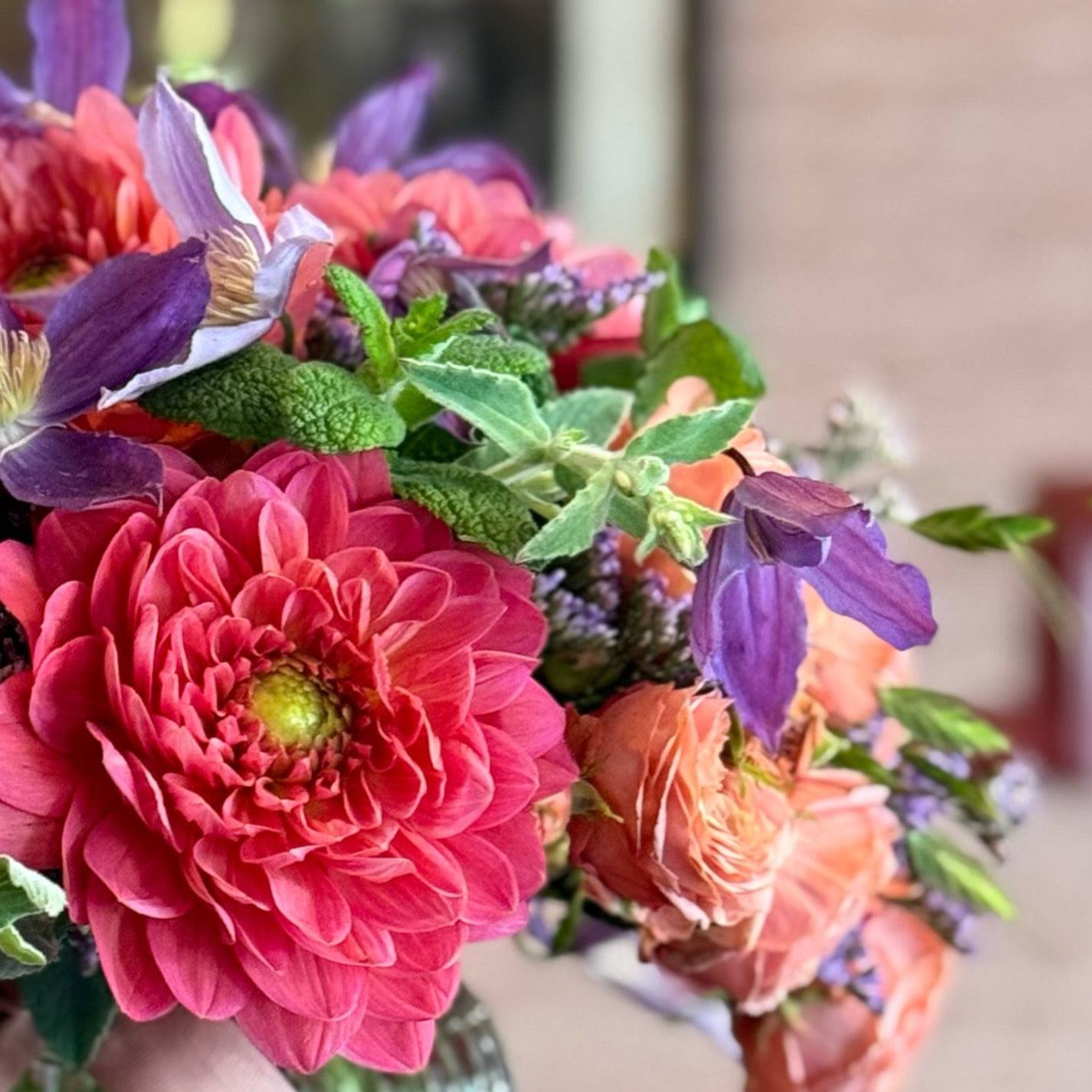Close-up of Summer Thrills Posy showing peach roses, dahlias and purple sea lavender in a vibrant summer arrangement, by Pulbrook & Gould London