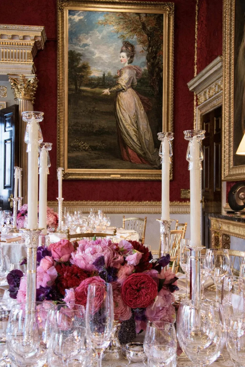 Grand English dining room tablescape with crystal candelabra, jewel-toned pink and burgundy florals, and, by Pulbrook & Gould