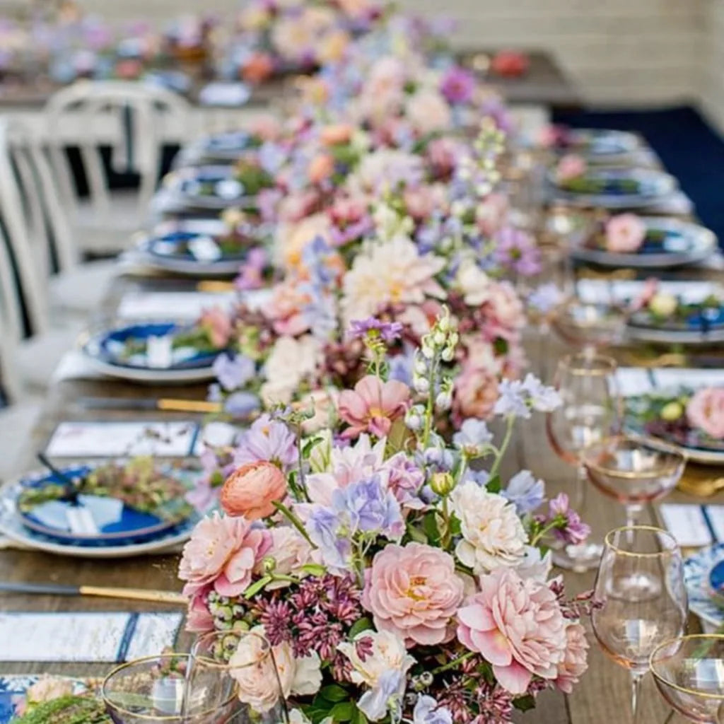 Long outdoor banquet table styled by Pulbrook & Gould with a flowing runner of pastel pink, lilac and peach flowers.