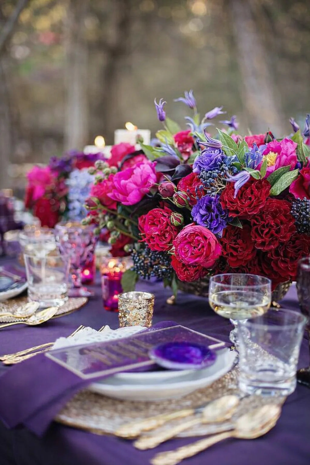 Evening tablescape by Pulbrook & Gould with a jewel-toned purple and magenta floral centrepiece on a deep purple linen table.
