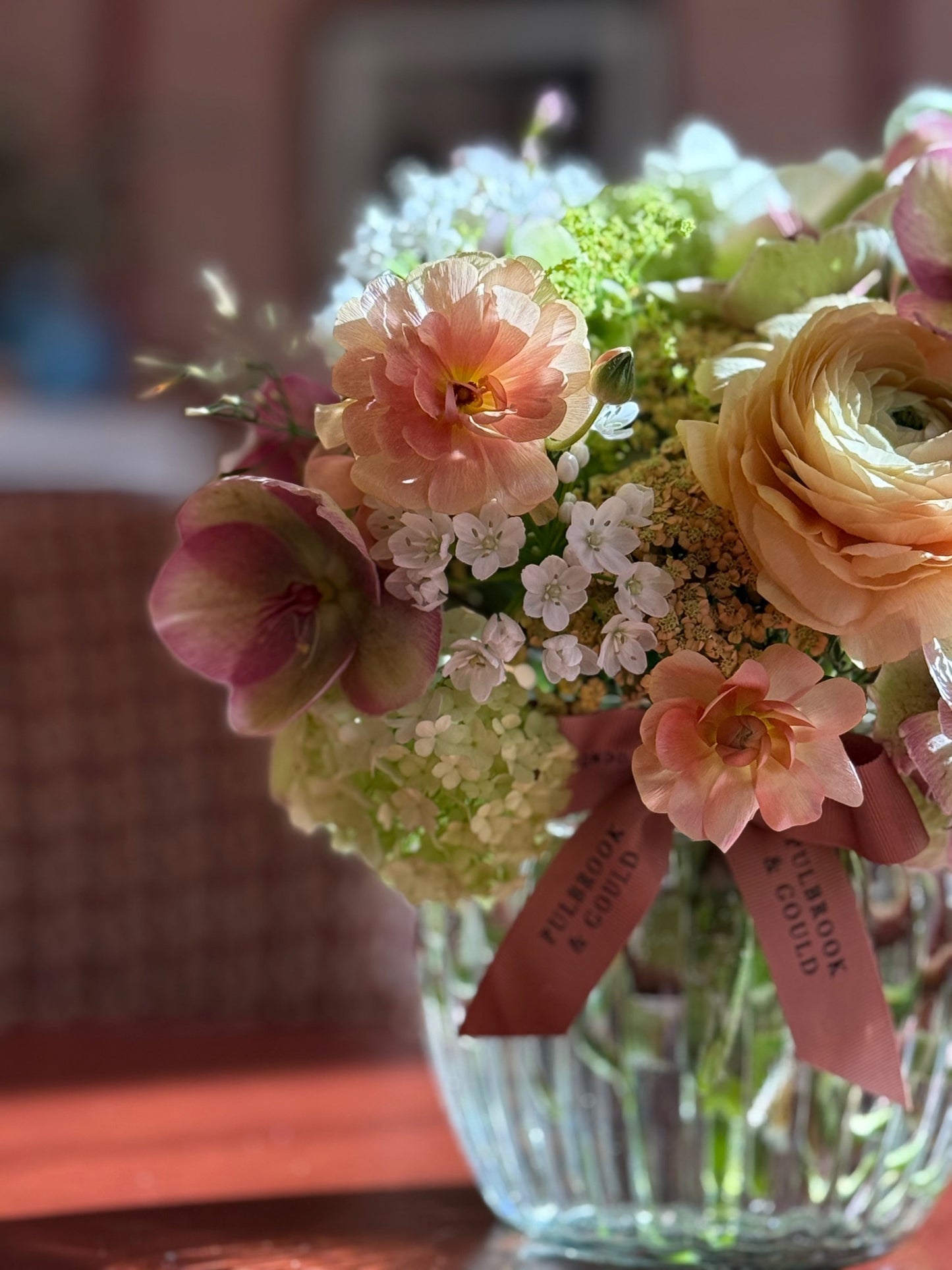 Bouquet of flowers with a pink ribbon in a clear vase on a blurred background