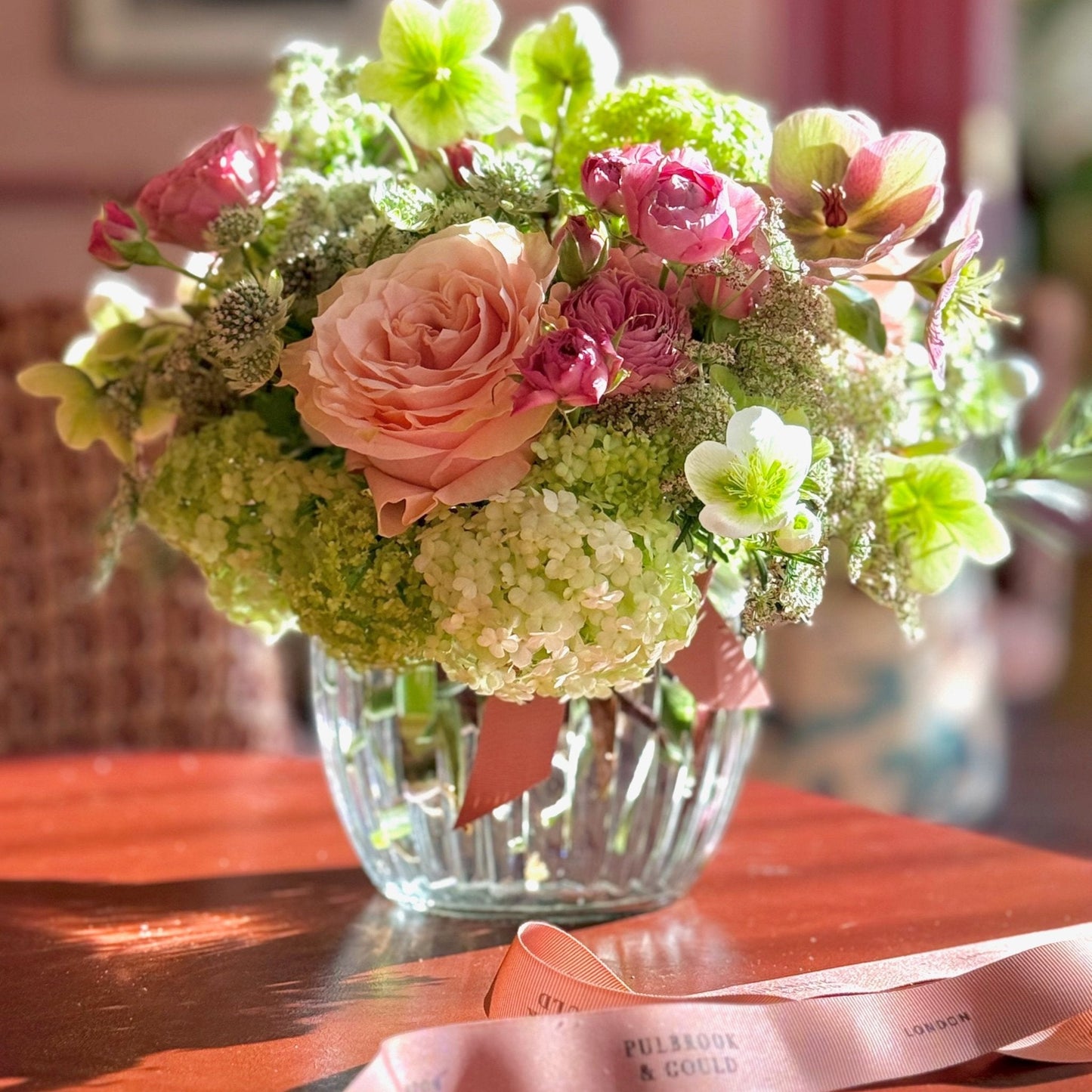 Bouquet of flowers in a clear vase on a wooden table with a blurred background