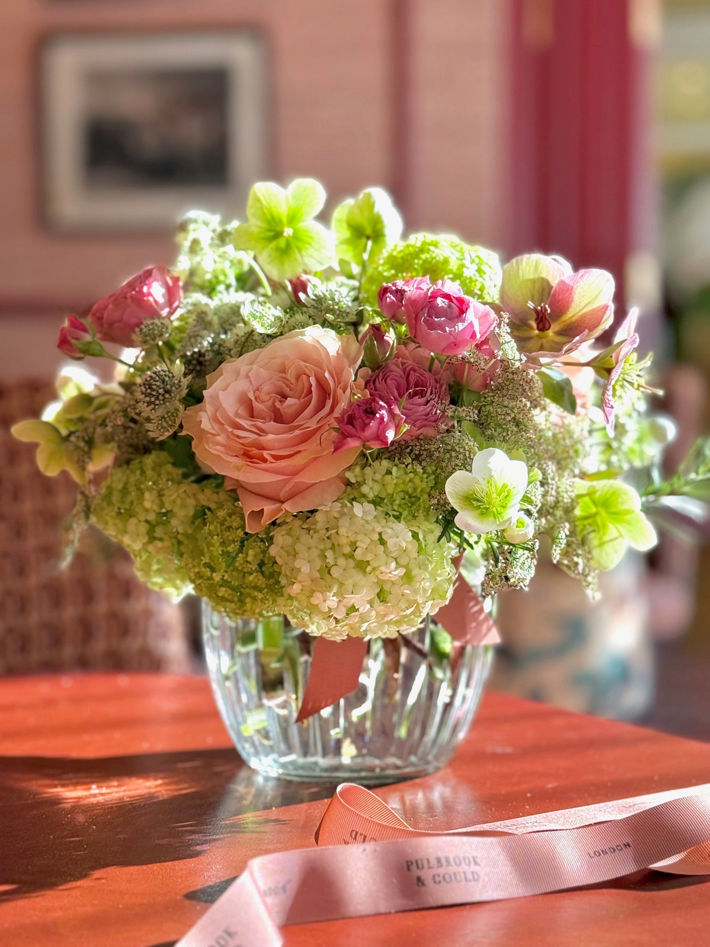 Bouquet of flowers in a clear vase on a wooden table with a blurred background