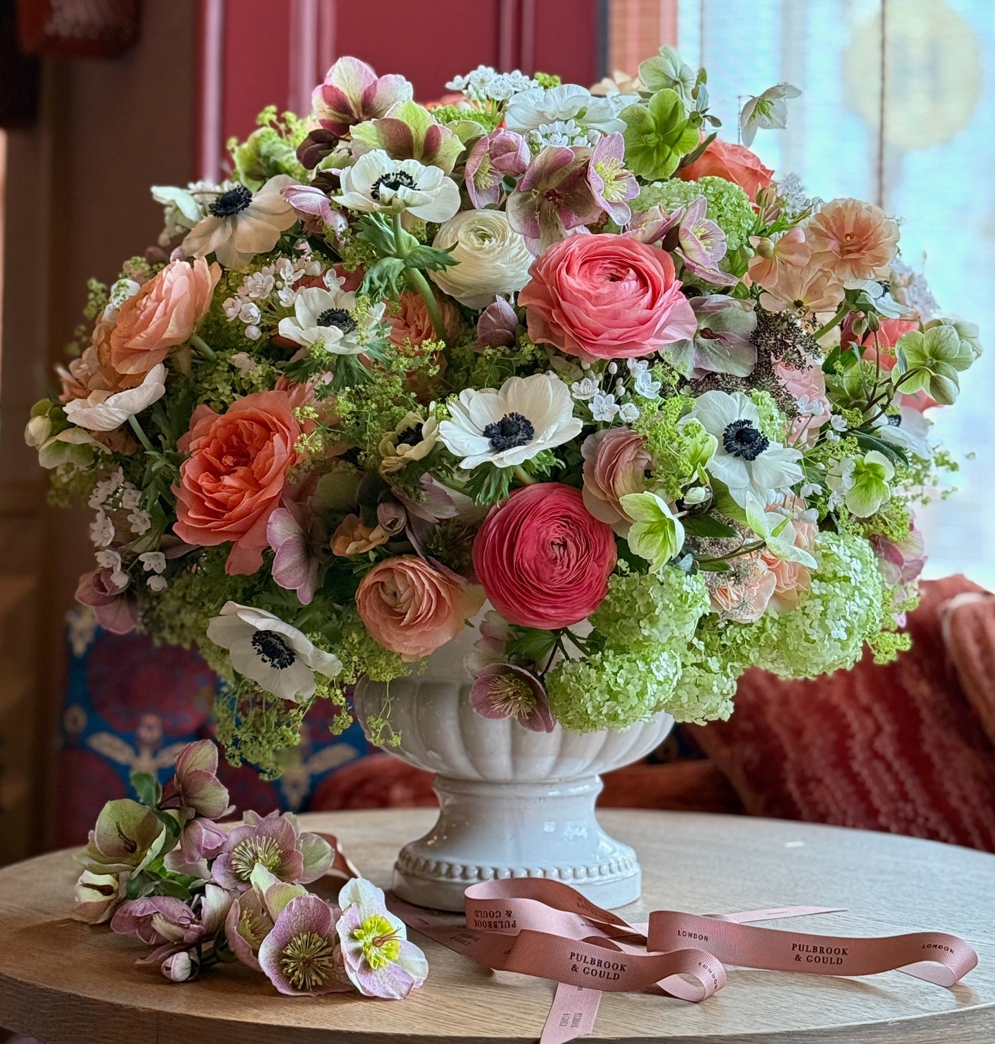 Colorful floral arrangement in a white vase on a wooden table with a blurred background