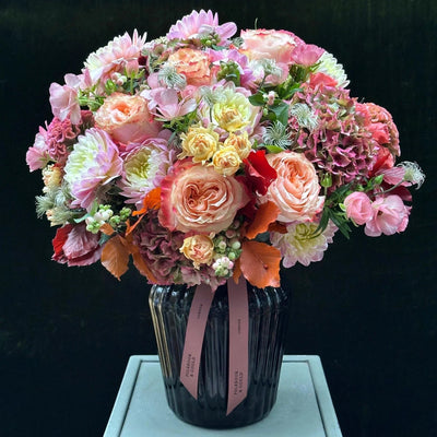 
                    
                      The Beaufort by Pulbrook and Gould hand-tied bouquet and vase arrangement in pink and cream with autumn foliage
                    
                  
