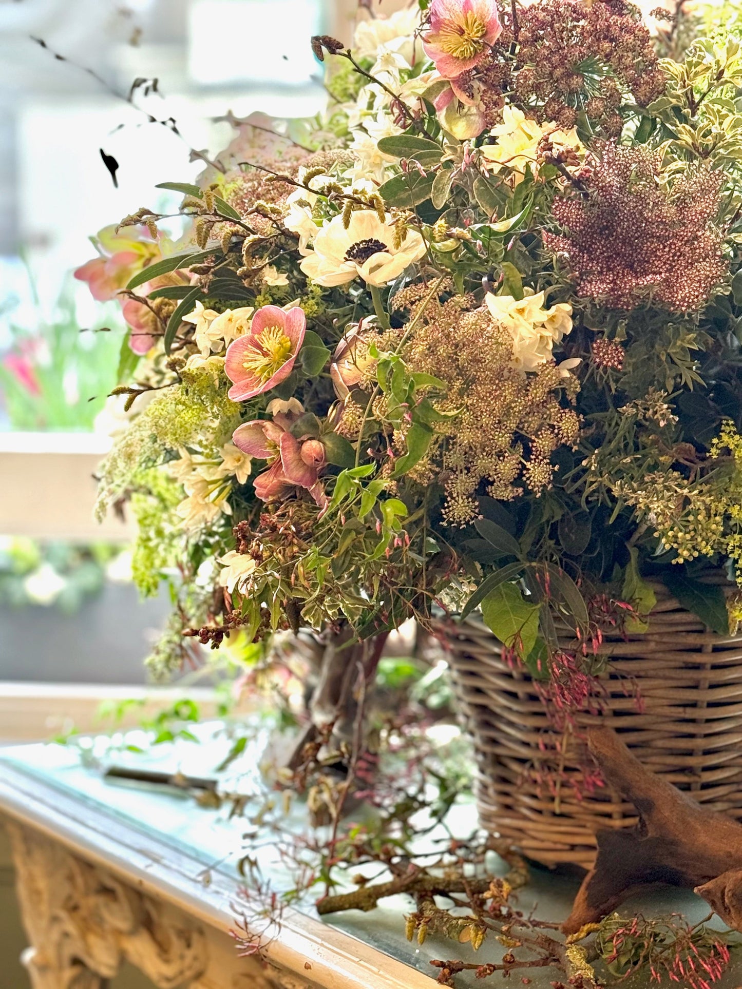 Decorative floral arrangement in a wicker basket on a reflective surface with a blurred background