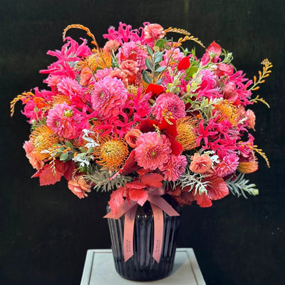 
                    
                      The Rutland by Pulbrook and Gould hand tied bouquet and vase arrangement in pink, orange and red autumn blooms
                    
                  