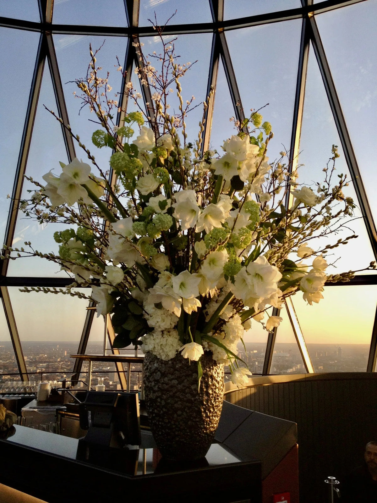 White seasonal flower arrangement at sunset inside the Gherkin, 30 St Mary Axe, weekly contract flowers, by Pulbrook & Gould
