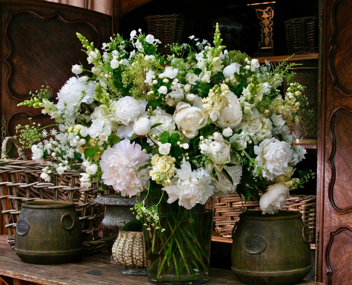 Large white and cream peony arrangement flanked by antique bronze urns, weekly contract flowers by Pulbrook & Gould, London