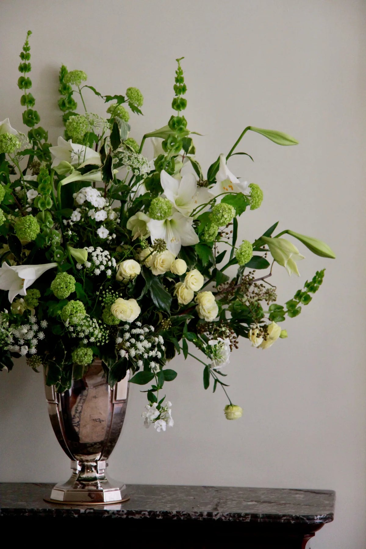 White and green lily arrangement in a silver urn on a marble console table, weekly contract flowers, by Pulbrook & Gould