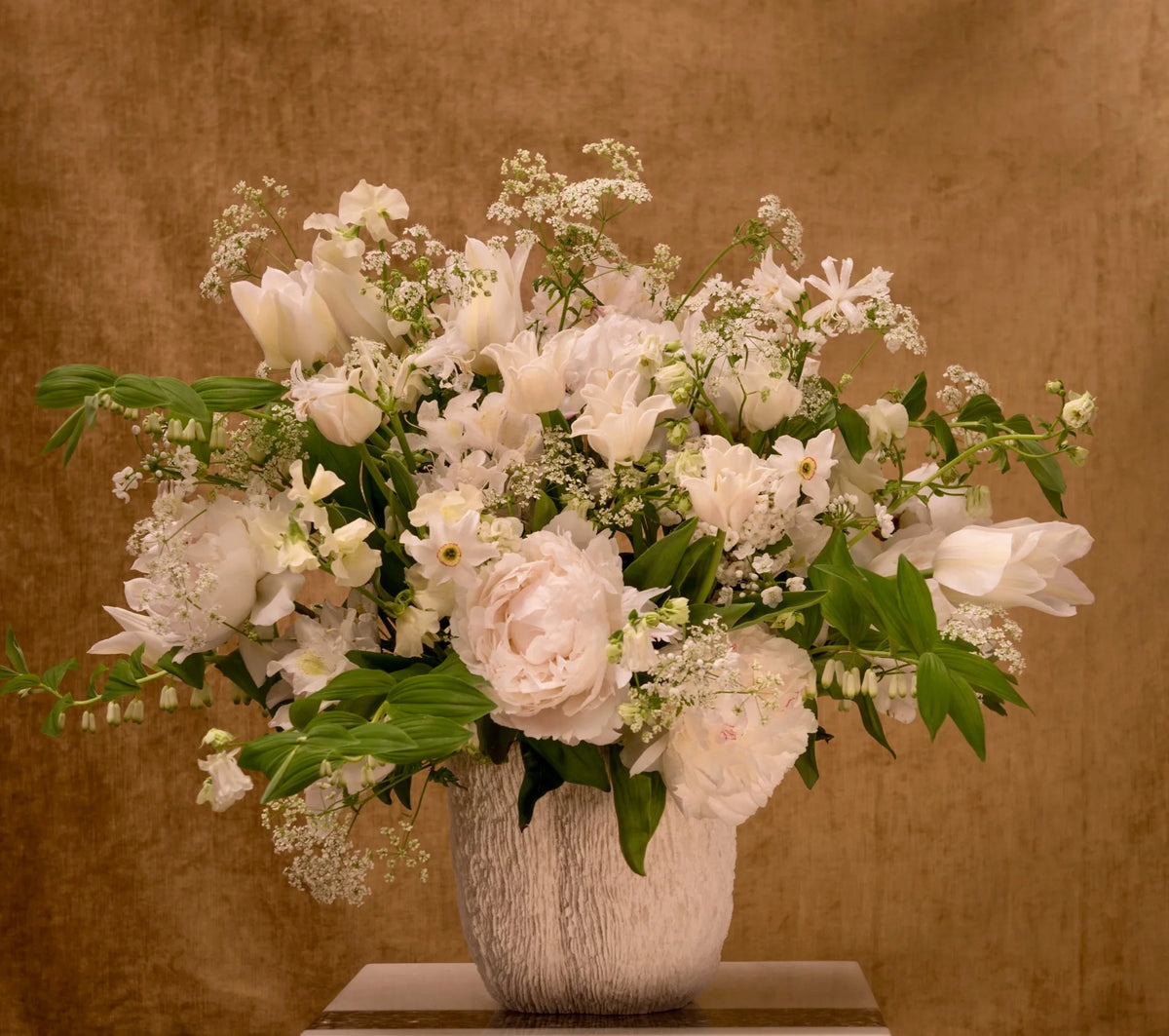 Soft white and blush peony and tulip arrangement in a textured ceramic vase, weekly flowers by Pulbrook & Gould, London