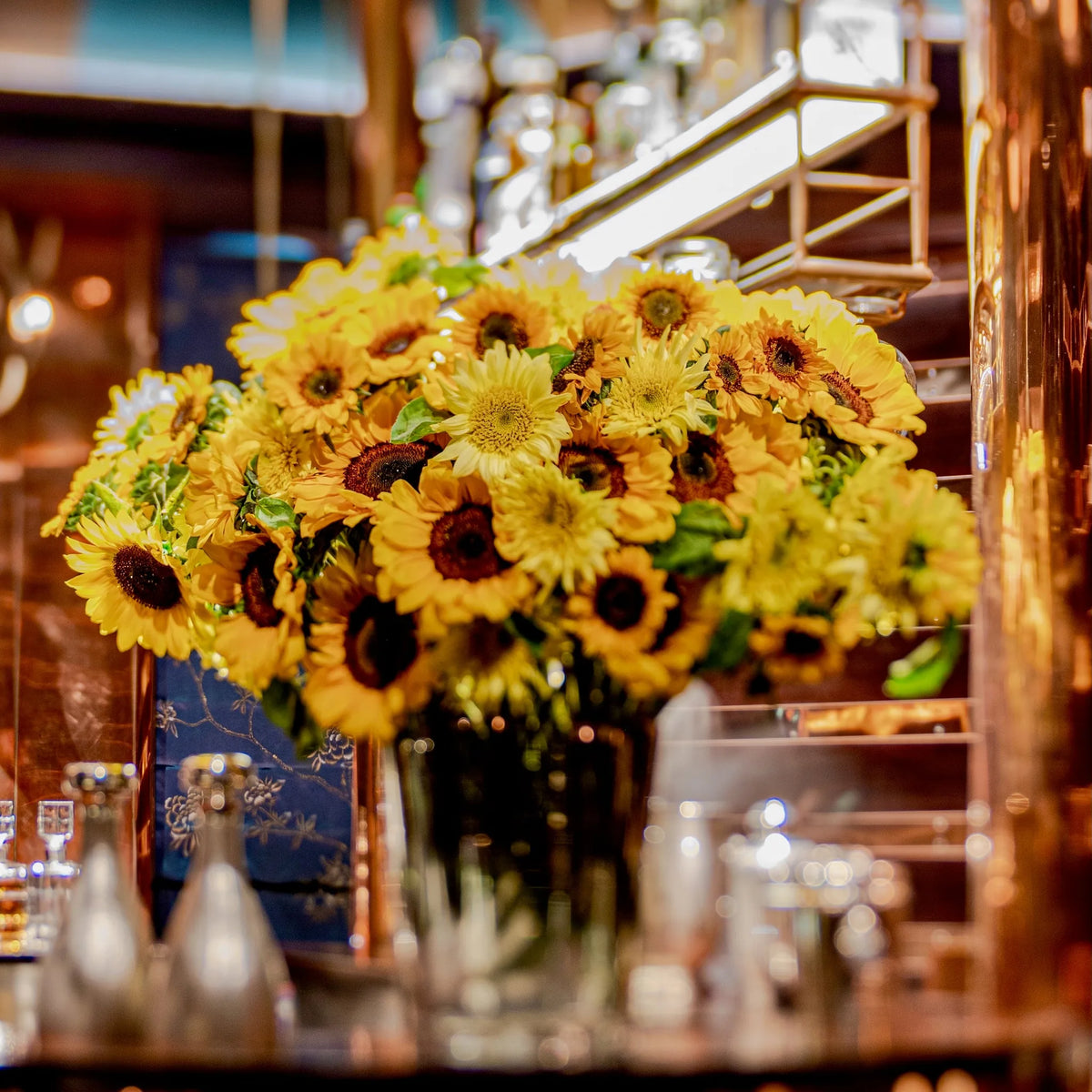 Bright yellow sunflower arrangement on a restaurant bar counter, weekly contract flowers by Pulbrook & Gould, London