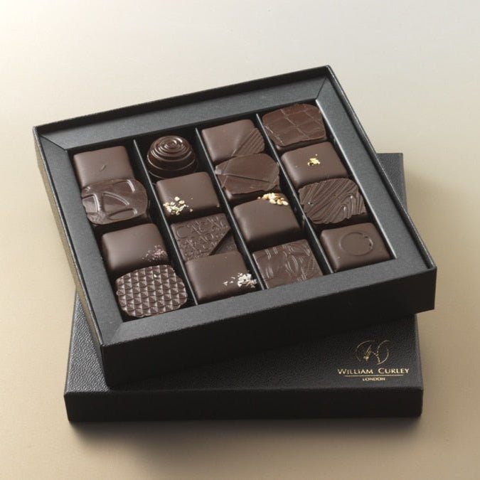 A box of William Curley handmade chocolates containing 16 pieces of various shapes and designs, displayed on a neutral background.