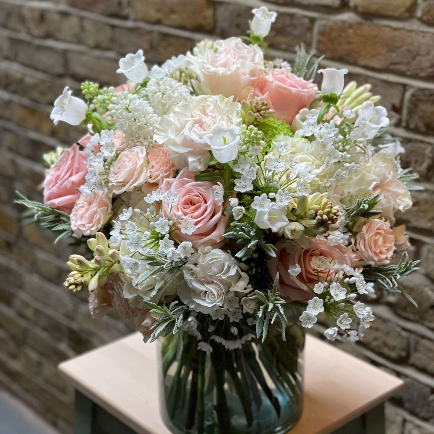 Victoria Mother's Day flower arrangement by Pulbrook & Gould — Quicksand roses, freesias, hydrangeas and waxflower displayed on a wooden stool